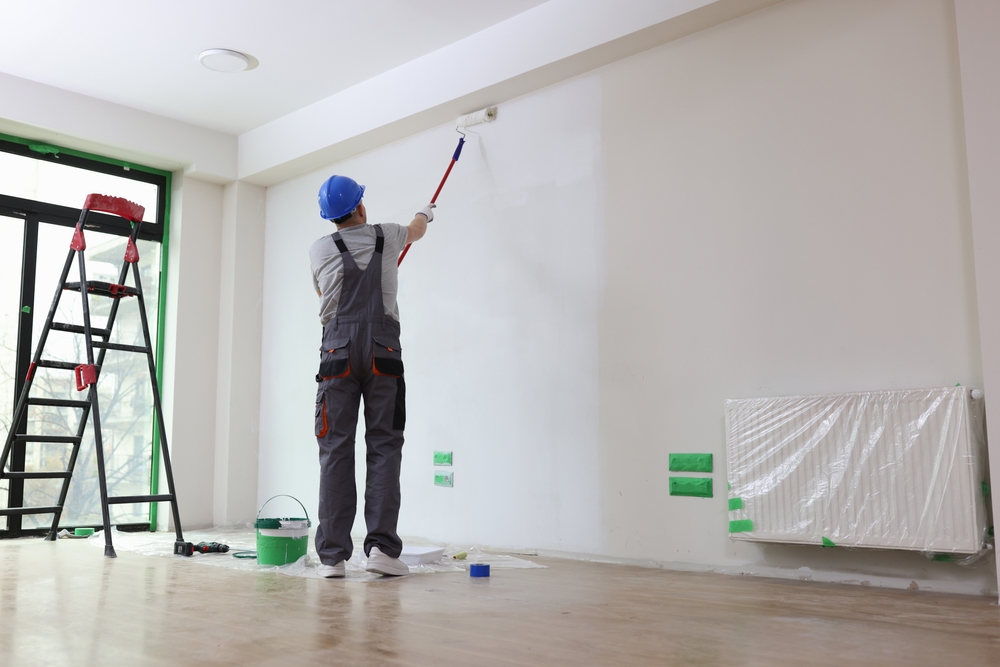 Een professionele schilder aan het werk, met precisie en zorg een muur schilderend. Deze afbeelding illustreert het belang van vakmanschap en nauwkeurigheid bij het inhuren van een schilder per uur.